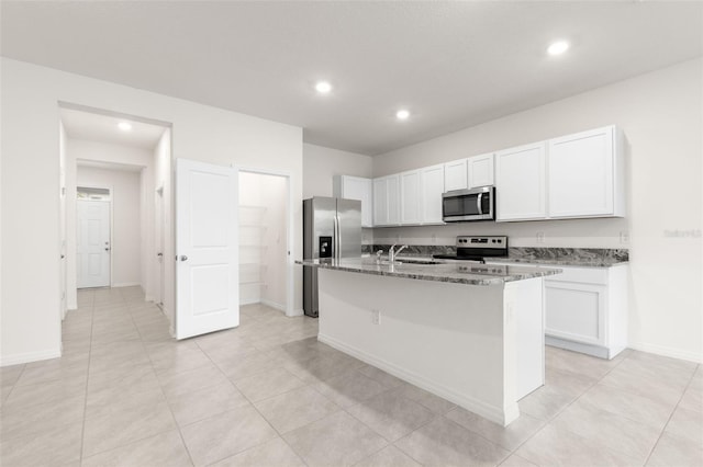 kitchen featuring sink, white cabinetry, dark stone counters, an island with sink, and stainless steel appliances