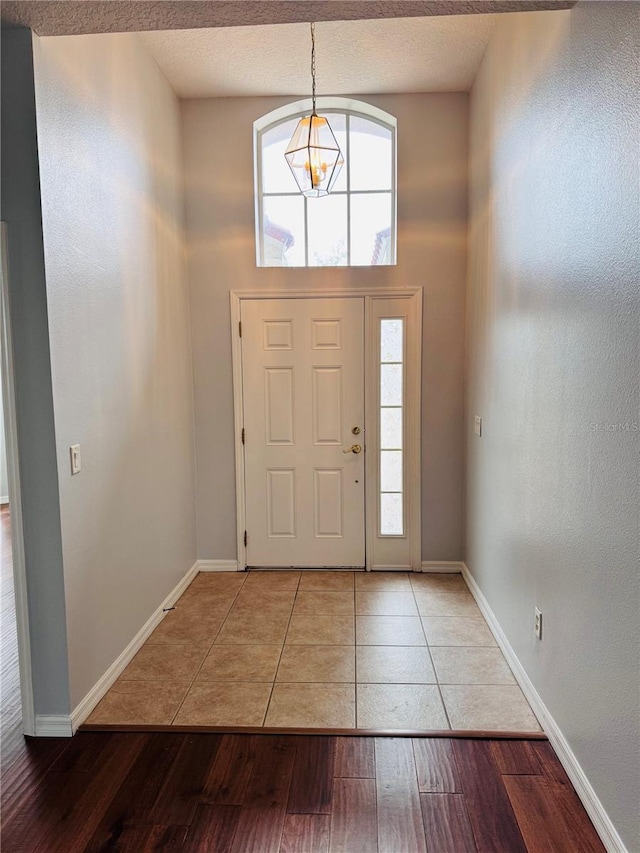 foyer with hardwood / wood-style floors, a towering ceiling, and a notable chandelier