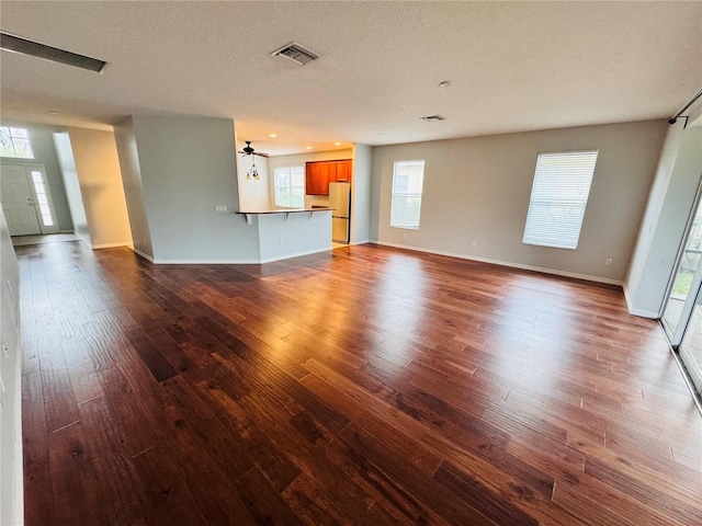 unfurnished living room featuring wood-type flooring, a textured ceiling, and ceiling fan