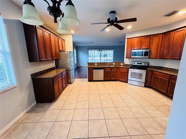 kitchen featuring dark stone counters, sink, ceiling fan, light tile patterned floors, and stainless steel appliances