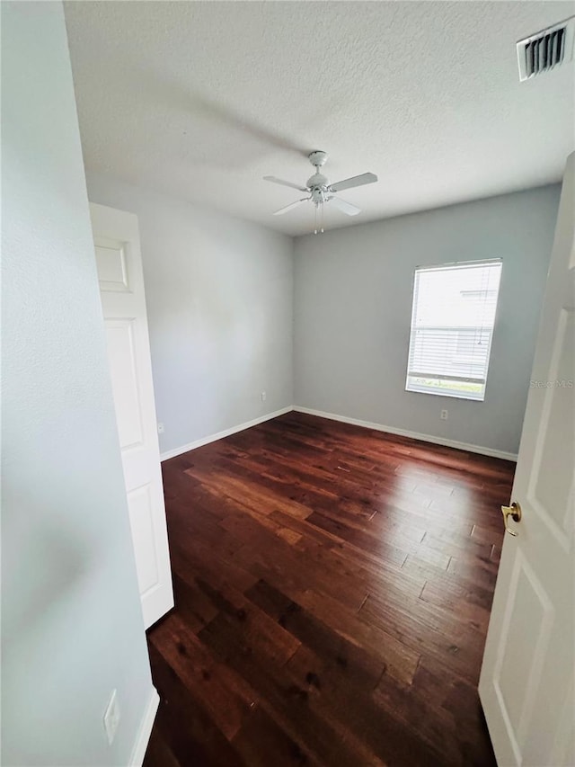 spare room with dark hardwood / wood-style floors, ceiling fan, and a textured ceiling