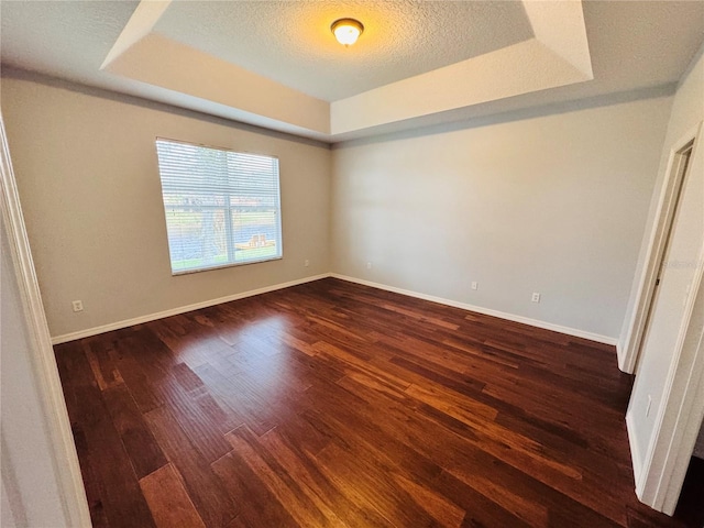 unfurnished bedroom featuring a raised ceiling, a textured ceiling, and dark hardwood / wood-style floors