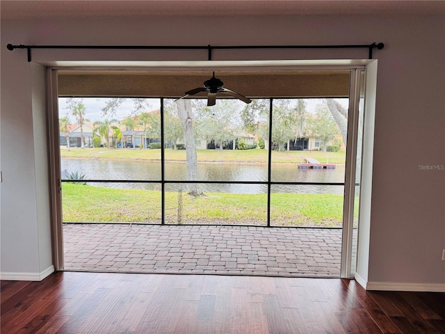 entryway featuring ceiling fan, dark hardwood / wood-style flooring, a water view, and a healthy amount of sunlight