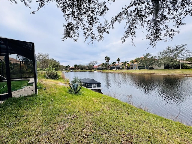 dock area with a yard, a water view, and a lanai