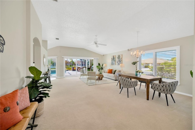 carpeted dining area with vaulted ceiling, a textured ceiling, a healthy amount of sunlight, and ceiling fan with notable chandelier