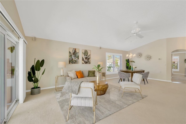 carpeted living room featuring ceiling fan with notable chandelier and lofted ceiling