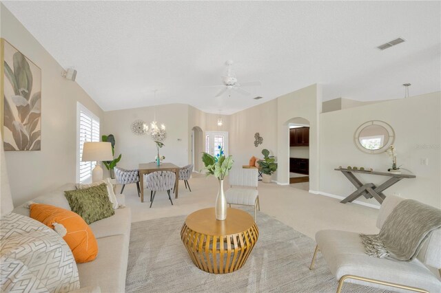 carpeted living room with ceiling fan with notable chandelier and a textured ceiling