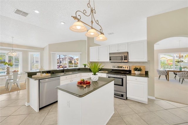 kitchen with stainless steel appliances, sink, decorative light fixtures, a kitchen island, and lofted ceiling