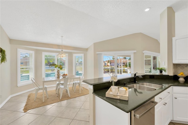 kitchen with kitchen peninsula, vaulted ceiling, sink, dishwasher, and white cabinetry