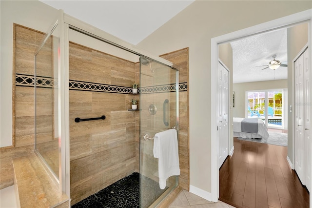 bathroom featuring a shower with shower door, a textured ceiling, ceiling fan, hardwood / wood-style flooring, and lofted ceiling