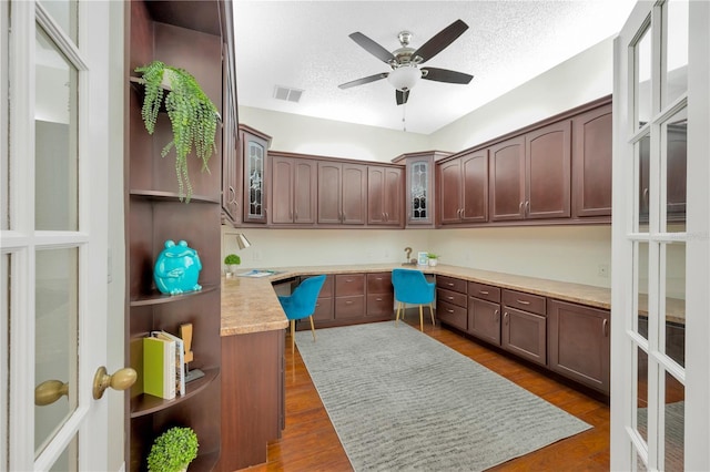 kitchen with ceiling fan, light stone countertops, a textured ceiling, dark hardwood / wood-style flooring, and dark brown cabinetry