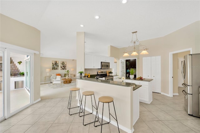 kitchen featuring kitchen peninsula, white cabinets, pendant lighting, and appliances with stainless steel finishes