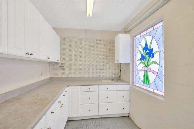 kitchen with white cabinetry, a healthy amount of sunlight, and a textured ceiling