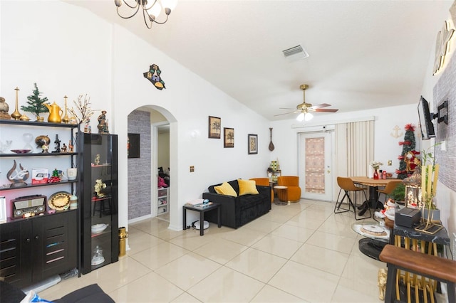 living room with ceiling fan with notable chandelier, light tile patterned floors, and vaulted ceiling