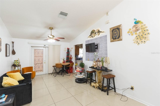 living room featuring ceiling fan, light tile patterned floors, and vaulted ceiling