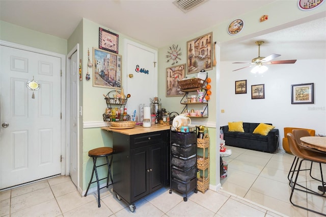 kitchen featuring ceiling fan, light tile patterned flooring, and wooden counters