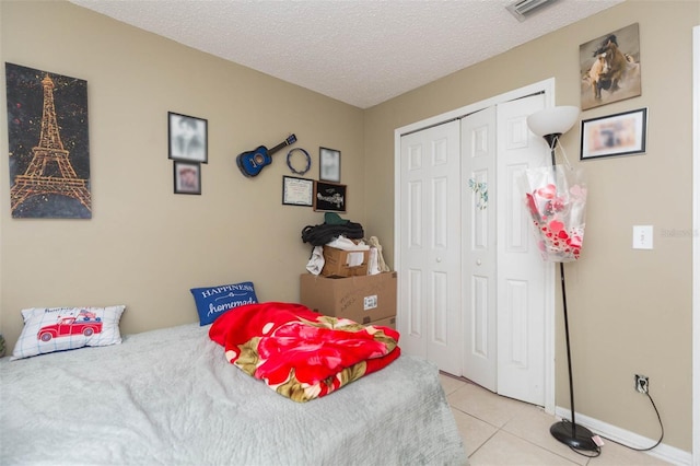 tiled bedroom with a textured ceiling and a closet