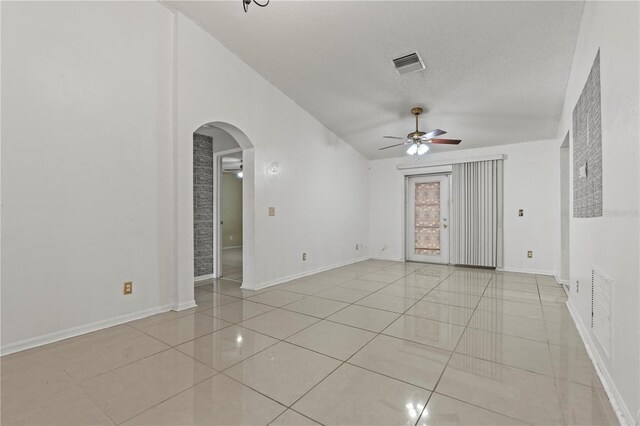 empty room featuring light tile patterned floors, arched walkways, visible vents, and a ceiling fan