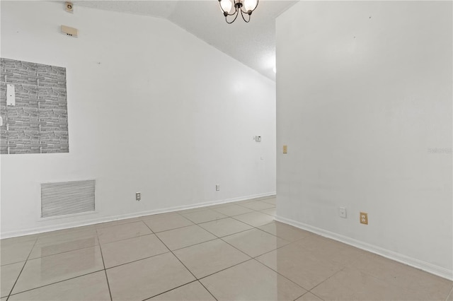 tiled empty room with lofted ceiling, visible vents, and baseboards