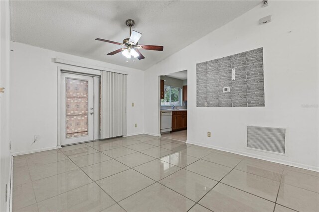 spare room with light tile patterned floors, ceiling fan, visible vents, baseboards, and vaulted ceiling