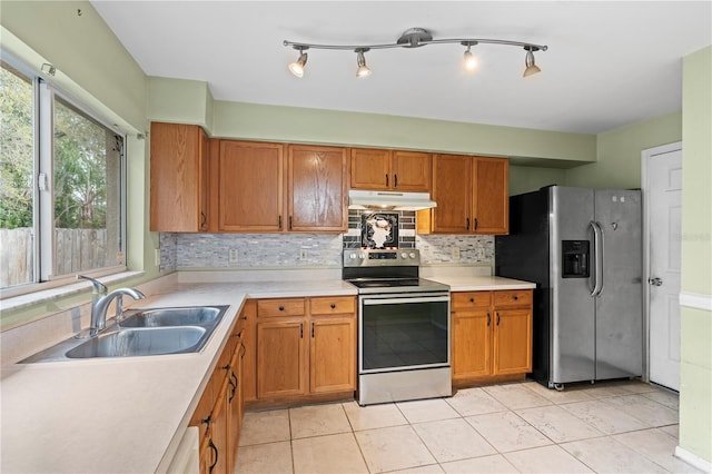 kitchen with tasteful backsplash, light countertops, appliances with stainless steel finishes, a sink, and under cabinet range hood