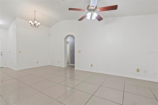 unfurnished room with arched walkways, vaulted ceiling, a textured ceiling, and light tile patterned floors