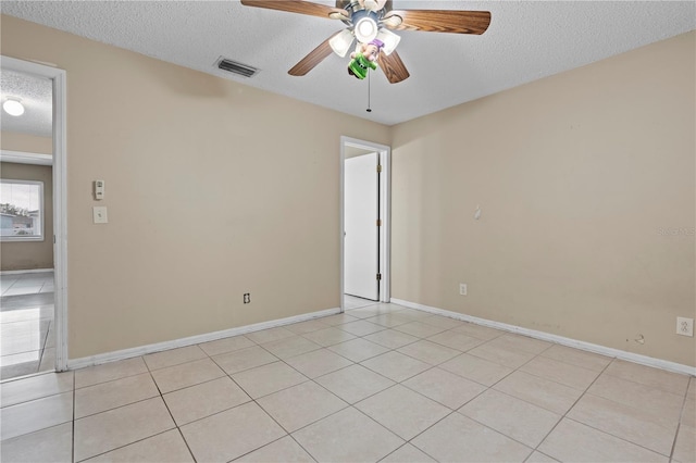 empty room featuring visible vents, a textured ceiling, baseboards, and light tile patterned floors