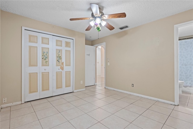 unfurnished bedroom featuring visible vents, a textured ceiling, baseboards, and light tile patterned flooring