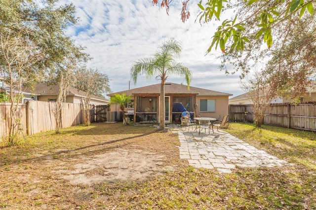 back of property featuring a sunroom, a fenced backyard, a yard, and a patio