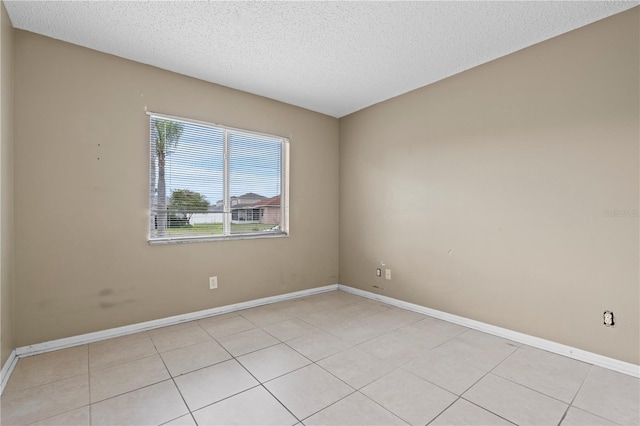 unfurnished room featuring a textured ceiling, baseboards, and light tile patterned floors