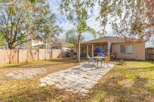 view of yard featuring a sunroom, a fenced backyard, and a patio