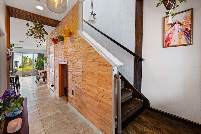 stairway with tile patterned floors, beam ceiling, and wood walls