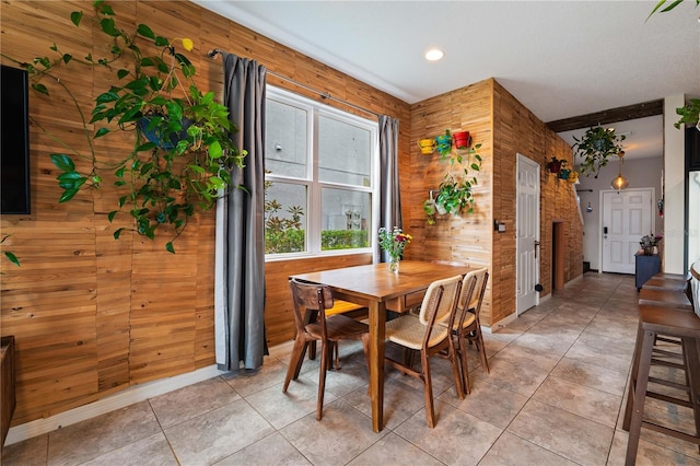 tiled dining room featuring wood walls