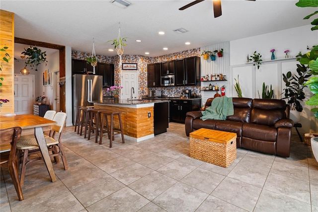 kitchen with stainless steel appliances, a kitchen island, light tile patterned floors, and a kitchen breakfast bar