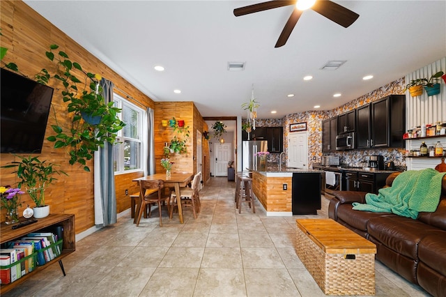 kitchen featuring appliances with stainless steel finishes, sink, a center island, light tile patterned floors, and dark brown cabinetry