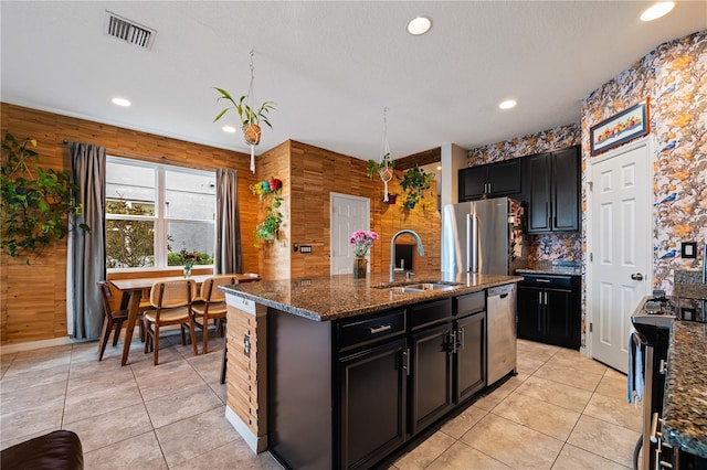 kitchen with an island with sink, appliances with stainless steel finishes, sink, and light tile patterned floors