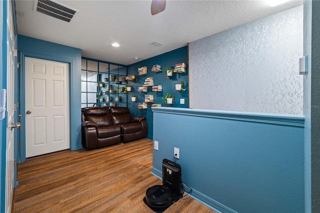 interior space with ceiling fan, hardwood / wood-style floors, and a textured ceiling