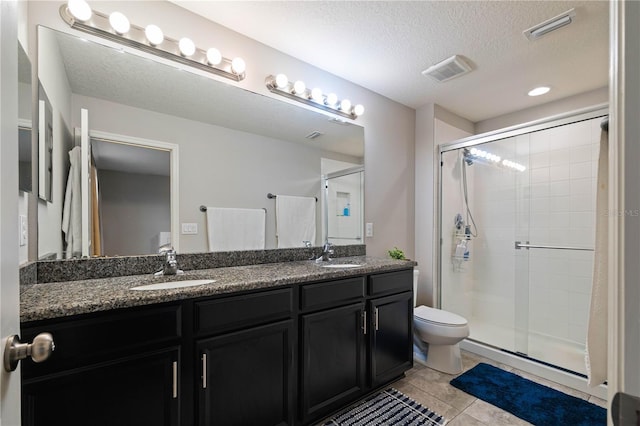 bathroom with walk in shower, toilet, a textured ceiling, vanity, and tile patterned flooring