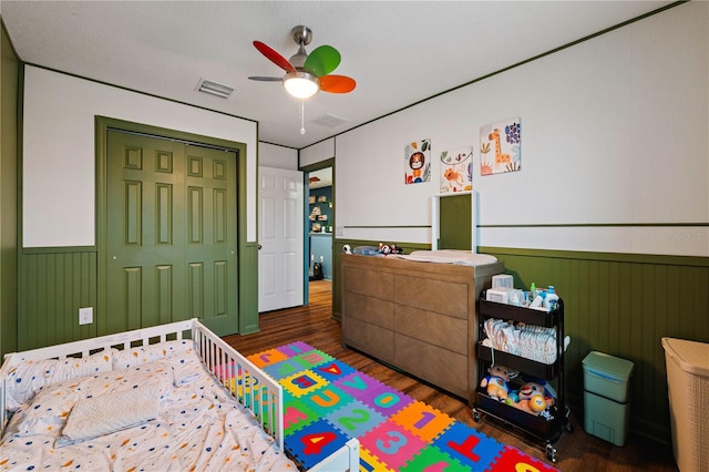 bedroom featuring dark hardwood / wood-style floors, a closet, ceiling fan, and wood walls