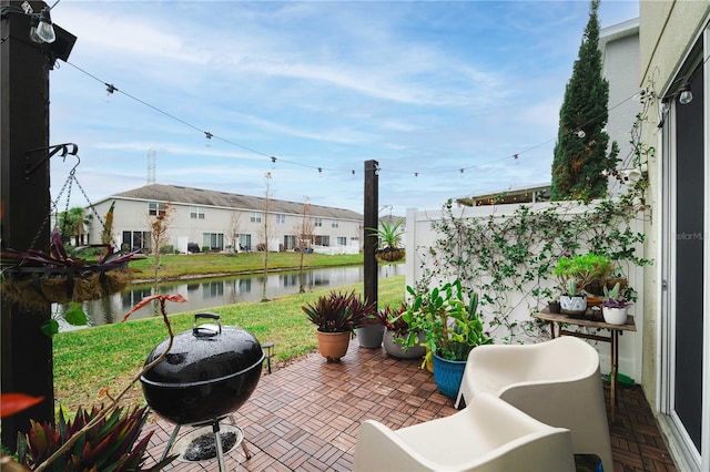 balcony with a water view, grilling area, and a patio area