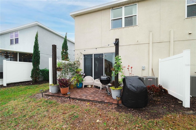 back of property featuring central AC unit, a patio, and a lawn