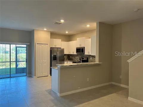 kitchen with kitchen peninsula, decorative backsplash, white cabinetry, and stainless steel appliances