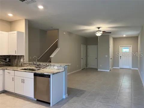 kitchen with tasteful backsplash, kitchen peninsula, white cabinets, and stainless steel dishwasher