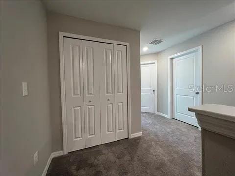 unfurnished bedroom with dark colored carpet and a closet