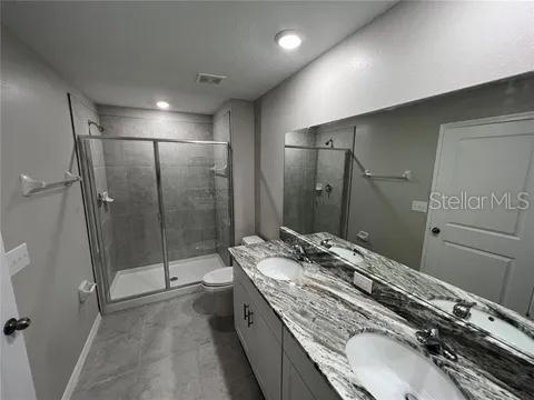 bathroom with vanity, a shower with shower door, and toilet