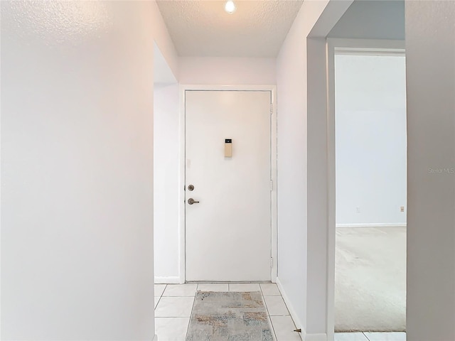 doorway to outside with light tile patterned floors and a textured ceiling