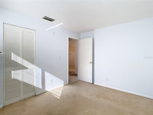 spare room featuring light carpet and a textured ceiling