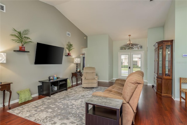 living room with dark hardwood / wood-style floors, an inviting chandelier, lofted ceiling, and french doors