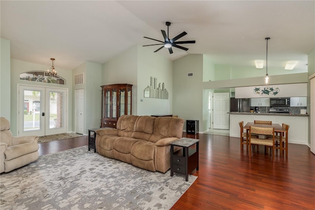 living room featuring french doors, ceiling fan with notable chandelier, high vaulted ceiling, and dark wood-type flooring