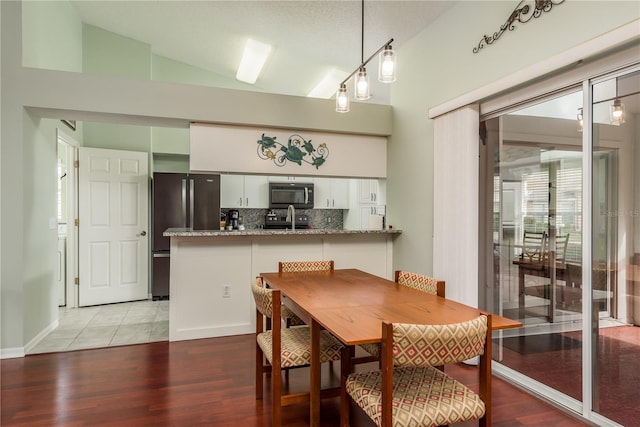 dining area featuring sink, light hardwood / wood-style flooring, and vaulted ceiling